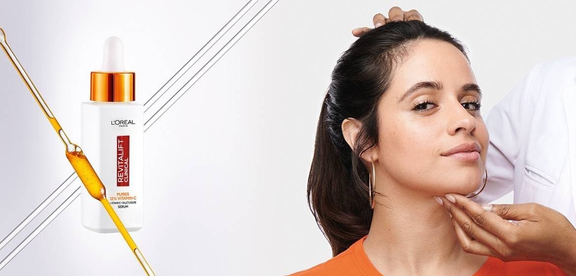 Dermatologin untersucht das Gesicht. von Camila Cabello und daneben das Clinical Vitamin C Serum